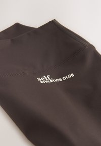 Fekete sportos felső sima anyagból, varrott varrással és egy fehér, "self. ATHLETICS CLUB" feliratú logóval. Egyszerű kialakítás, testhezálló szabás.