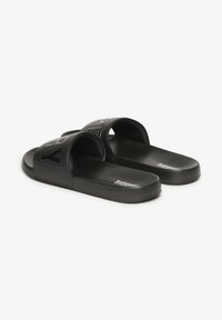Sorte glidende sandaler med to brede remme med prægede logoer, en glat mat finish og en lavprofil sål. Struktureret fodbede for komfort.