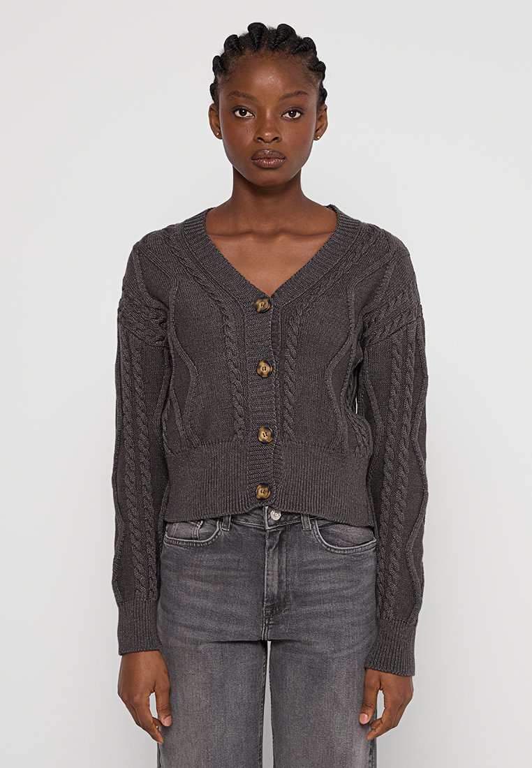 Grijze gebreide cardigan met een V-hals, versierd met kabelpatronen, lange mouwen en vier houten knopen aan de voorkant.