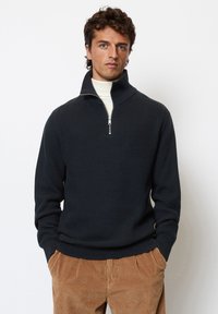 Dark navy pullover sweater with a zippered mock neck, textured knit pattern, and ribbed cuffs. Paired with light brown corduroy pants.