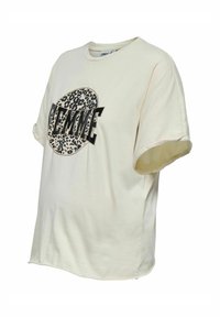 Camiseta de algodón crema con mangas cortas enrolladas, que presenta un gráfico en negro y estampado de leopardo que dice "FEMME" en letras negritas.
