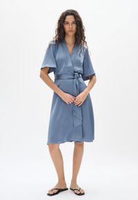 Blaues Wickelkleid mit kurzen Ärmeln und einem Bindegürtel. Aus glattem Stoff mit fließender Silhouette, ausgestattet mit einem knielangen Saum und schlichtem Design.