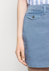 Ljusblå denimkjol med fickdetaljer, rak skärning och uppvikt kant. Mjuk textur och diskret sömnad längs kanterna.