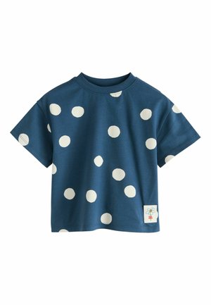 Niebieska bawełniana koszulka z dużymi białymi kropkami, okrągłym dekoltem i krótkimi rękawami. Zawiera małą ozdobną metkę z motywem kwiatu.
