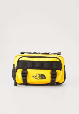 Sac banane compact jaune vif avec des sangles et boucles noires, logo The North Face au centre avant, et compartiments zippés.