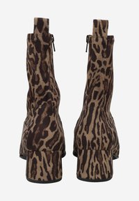 Bottines à imprimé léopard avec une texture lisse, de petits talons bloc et des fermetures éclair sur le côté, présentant un schéma de couleurs marron et beige.