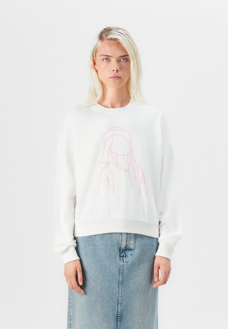 Felpa bianca con un disegno a linea rosa chiaro sul davanti. Presenta un collo a giro e polsini a costine, abbinata a una gonna di jeans.