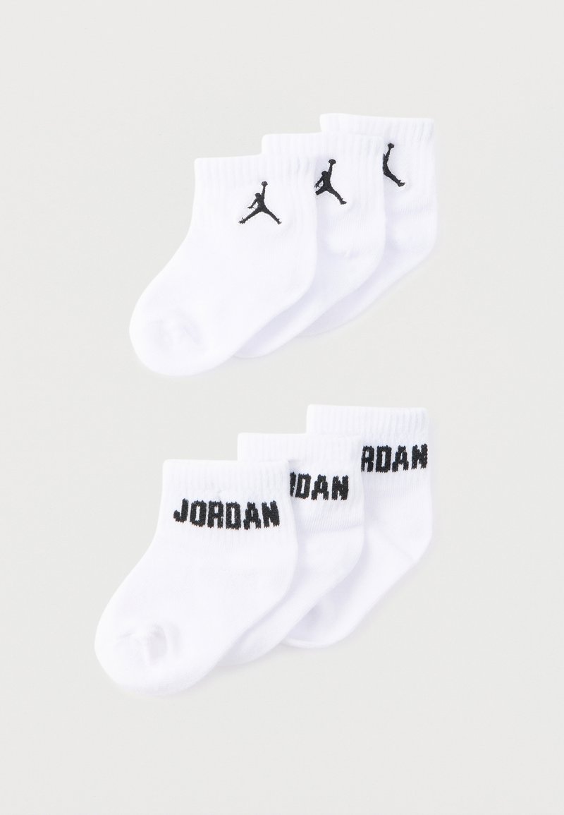 Τέσσερα ζευγάρια λευκές κάλτσες αστραγάλου, δύο με μαύρο λογότυπο Jumpman και δύο με το κείμενο "JORDAN" στη μανσέτα, τοποθετημένα σε λευκό φόντο.