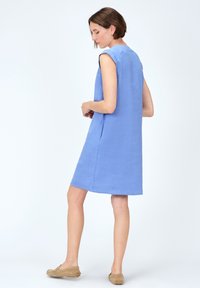 Ljusblå linnekjol med avslappnad passform, korta ärmar och rak nederkant. Har sidofickor och en detalj vid bakhalsen.