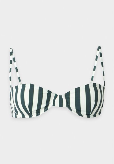 Haut de bikini rayé verticalement noir et blanc avec fines bretelles réglables sur fond gris clair.