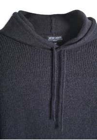 Tamno sivi vuneni pulover sa teksturiranim pletenjem, s kapuljačom i prednjim patentnim zatvaračem u visini polovine. Oznaka vidljiva s imenom brenda i veličinom.