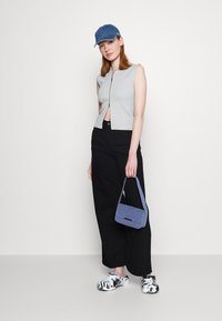 Gray sleeveless zip-up top, black wide-leg pants, blue denim cap, blue bag, and shiny patterned clogs. Minimalist and casual outfit.