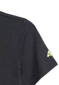 Détail d'une chemise noire à manches courtes montrant la couture d'épaule et un logo vert citron partiel sur la manche.