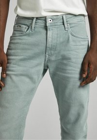Jeans in denim verde chiaro con vestibilità slim, caratterizzati da un classico design a cinque tasche e una leggera scoloritura sulle cosce, realizzati in morbido cotone.