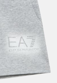 Halli puuvillane kangas pehme tekstuuriga, millel on valge logo print, kus on kirjas "EA7 EMPORIO ARMANI." Sisaldab küljetaskut.