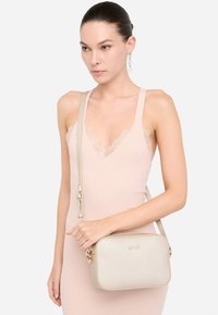 Borsa a tracolla con texture dorata, dalla forma rettangolare, dotata di una tracolla removibile e accessori dorati. Nome del marchio "LIU JO" impresso sul davanti.