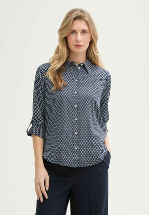 Blauwe en witte gestreepte blouse met een knoopsluiting aan de voorkant, lange mouwen opgerold en een klassieke kraag. Soepele textuur en een ontspannen pasvorm.
