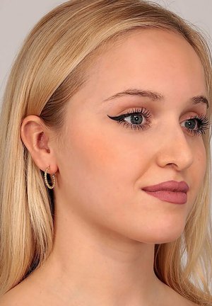 Goldene Creolen mit einem gedrehten Design, glänzender Oberfläche und kleinem Ösenverschluss. Das Modell zeigt ein natürliches Make-up und lange blonde Haare.