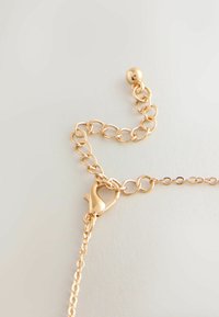 Guldfarvet kædearmbånd med sammenkædede ovale led, der har en hjerteformet lobsterlås og en lille rund perle som accent.