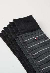 Calzini neri e grigi, con una texture a coste, con un paio che presenta righe orizzontali e un piccolo logo.