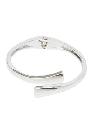 Bracelet ouvert en ton argent avec une fermeture à charnière et des extrémités effilées et arrondies sur un fond blanc.