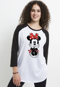 T-shirt raglan bianco e nero con una grafica di un personaggio dei cartoni animati che indossa un fiocco rosso a pois e dettagli coordinati. Tessuto morbido, vestibilità casual.