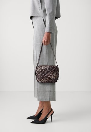 Personne portant un costume à carreaux noir et blanc tenant un sac à main imprimé léopard, portant des escarpins slingback noirs à talons pointus.