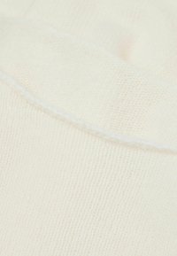 Tissu tricoté de couleur crème claire avec une texture douce et un subtil détail de côtes. Présente une couture contrastante blanche.