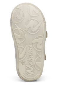 Světlý béžový podešev obuvi s texturovanou gumou, obsahující kruhové vzory a vyražený název značky "Naturino", navržena pro trakci a odolnost.