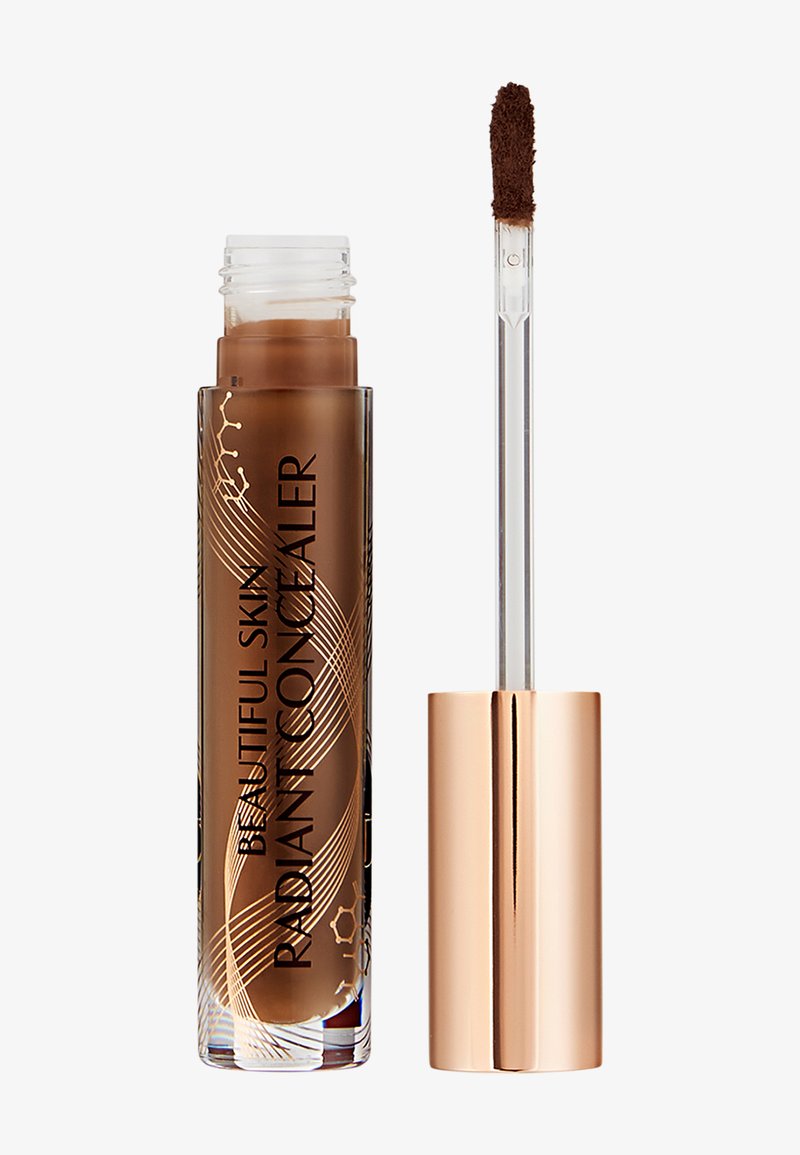 Tube de correcteur liquide marron étiqueté « Beautiful Skin Radiant Concealer » avec applicateur, le produit visible à l'extrémité.