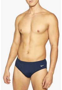 Bañadores azul marino hechos de tejido elástico, con un diseño ajustado, cinturilla elástica y un pequeño logotipo blanco de Nike en el lado izquierdo.