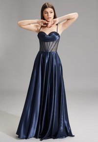 Abito da sera in satin blu navy con un corsetto trasparente aderente, scollatura a cuore e gonna fluente, caratterizzato da cuciture verticali e spalline sottili.