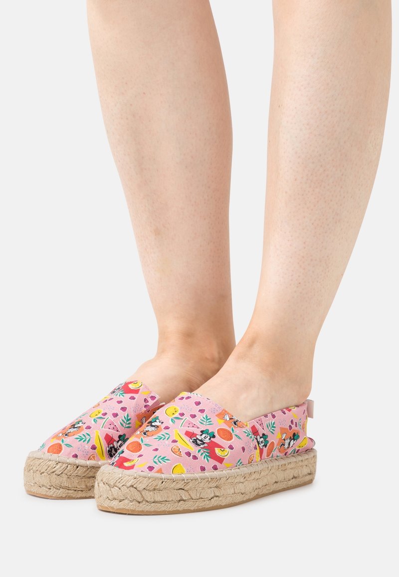 Espadrilles roses avec des imprimés de fruits et de fleurs colorés ; semelles en jute à finition texturée, style à enfiler, sans attaches visibles.