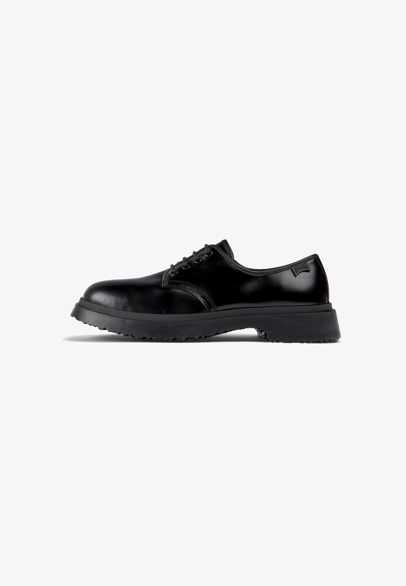 Chaussure noire en cuir à coupe basse avec semelle épaisse en caoutchouc, lacets à l'avant et logo de marque discret près du talon, vue de profil.