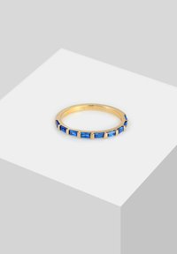 Anillo de oro con piedras preciosas azules rectangulares, con una banda lisa y acentos de piedras espaciados uniformemente, que exhibe un diseño geométrico.