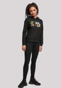 Black hoodie with colorful "Star Wars" graphic, kangaroo pocket, and ribbed cuffs. Paired with black leggings and black sneakers.