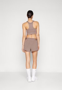 Lichtbruine atletische crop top en bijpassende shorts. De shorts hebben een losse pasvorm en beide stukken zijn gemaakt van zacht, rekbaar materiaal.