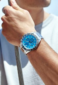 Ett armbandsur i rostfritt stål med en ljusblå urtavla, tre subdials, silverdetaljer och ett strukturerat armband.