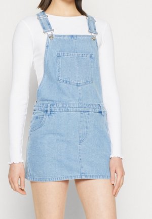 Robe salopette en denim bleu clair, avec des bretelles ajustables, une poche frontale et une taille cintrée avec une texture subtile.