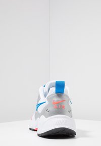 Baskets Nike Air en argent, blanc et rose, avec une tige en maille et cuir, dotées d'une accentuation bleue et d'une épaisse semelle noire.