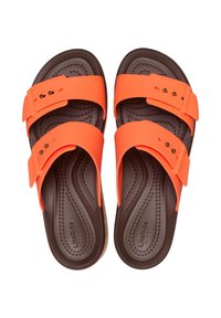 Sandales en plastique orange avec deux larges brides, semelle intérieure noire texturée et design léger. Comprend un logo subtil et des accents décoratifs en quincaillerie.