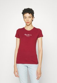 Bordo prigludusi marškinėliai trumpomis rankovėmis, su balta užrašu "Pepe Jeans London", centruotu krūtinės srityje. Minkšta medvilnė.