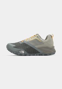 Gray and beige athletic shoes with a textured upper, reinforced toe, yellow accents, and a textured rubber sole for traction.