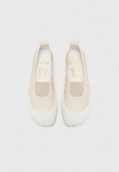 Beige Slippers bestehen aus einem glatten Material, haben einen elastischen Seiteneinsatz und eine weiße Gummisohle mit einer strukturierten Unterseite. Goldenes Logo im Inneren.