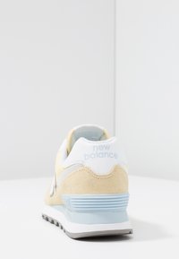 Sneaker i ruskind og mesh i lysegul med hvide og blå accenter, med polstret hæl og tekstureret ydersål for godt greb.