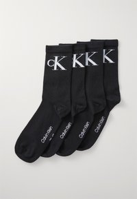 Black cotton socks featuring a ribbed cuff, cK logo in white on the front, and branding on the sole; includes four pairs in total.