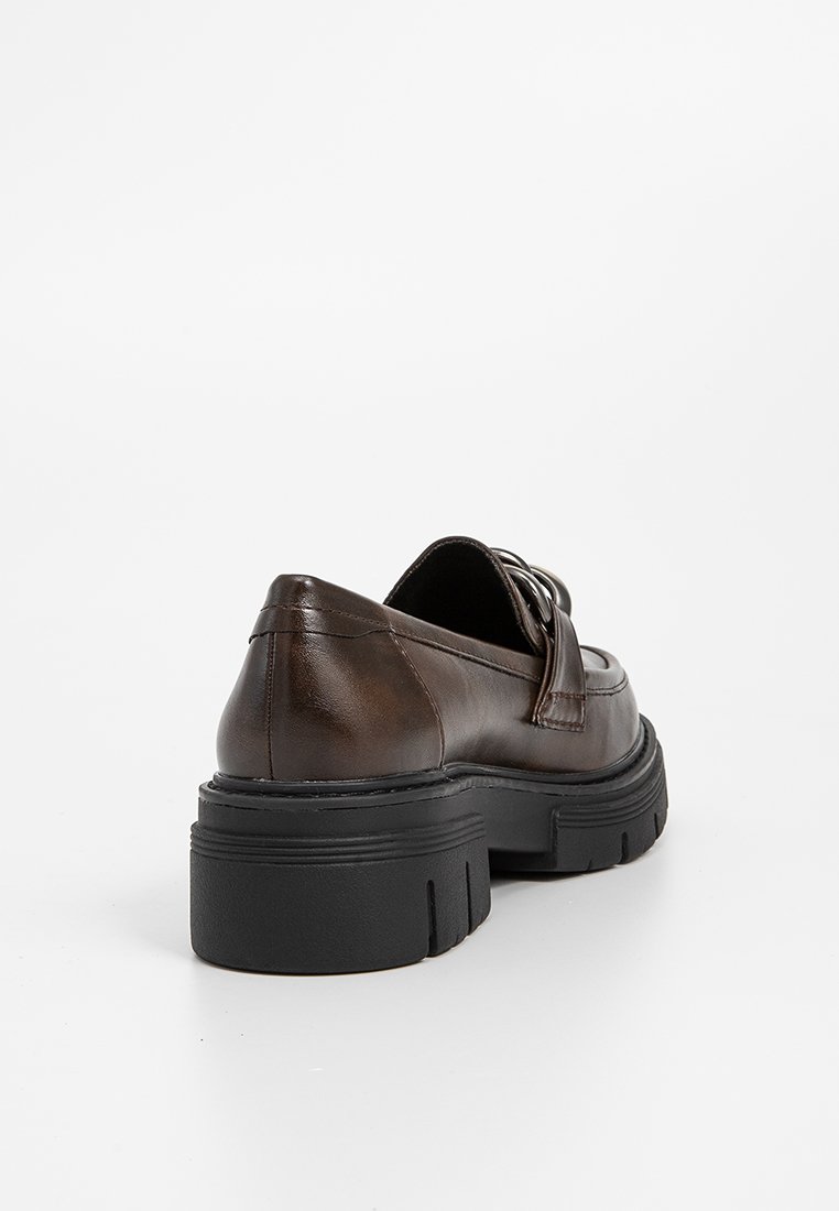Scarpa in pelle marrone con superficie liscia, suola nera spessa e dettaglio decorativo a fibbia sulla parte superiore. Forma della punta arrotondata, design a profilo basso.