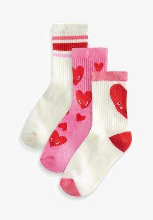 Tre paia di calze: una bianca con strisce rosse, una rosa con cuori rossi e una bianca con un grande motivo a cuore rosso. Texture a maglia, lunghezza a metà polpaccio.