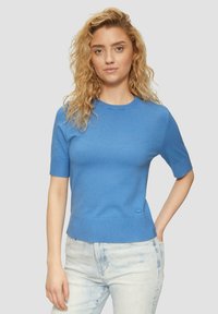 Haut à manches courtes, col rond en tissu tricoté bleu vif. Présente une taille ajustée et un détail de marque subtil sur l'ourlet.