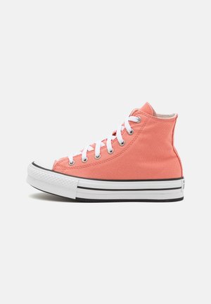 Zapatilla alta en lienzo color coral con cordones blancos, puntera de goma y media suela a rayas en blanco y negro. Textura suave con detalles de costura.